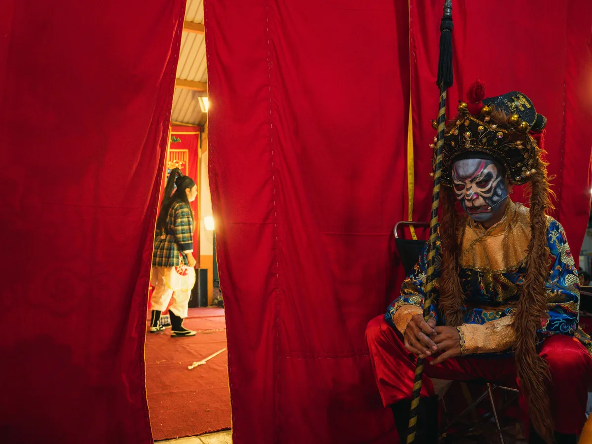 A backstage performer in traditional Chinese opera costume and painted face